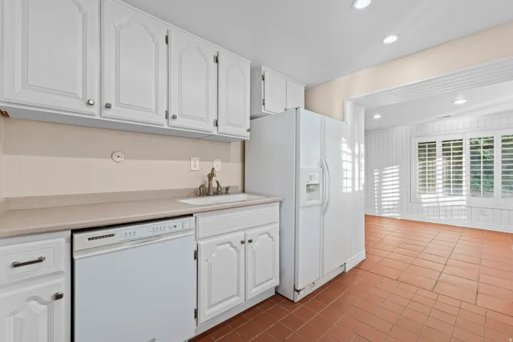 White kitchen cabinetry with integrated sink and chrome faucet