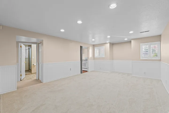 Recessed lighting, light-toned carpeting, wainscoting, and window shutters