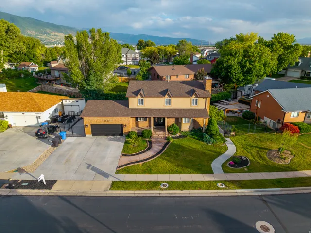 Two-story exterior with brick and stucco facade, attached garage, concrete driveway, and landscaped front yard with a curved pathway