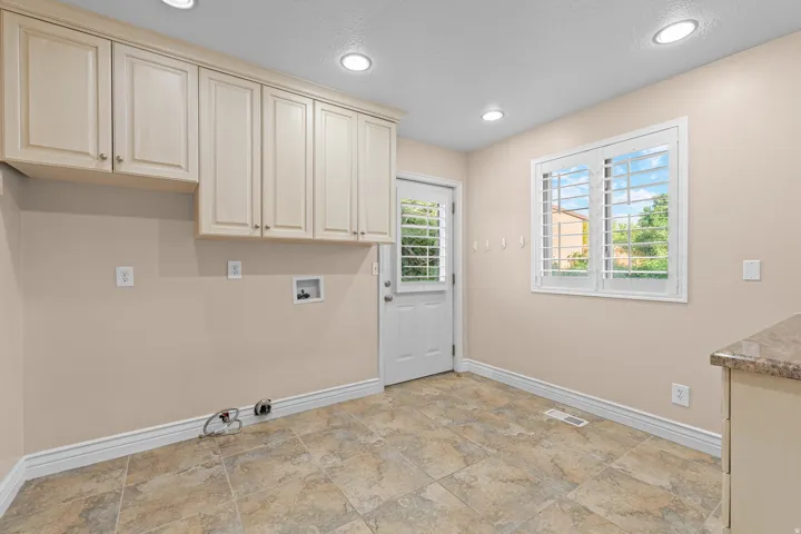 Recessed lighting, light-toned cabinetry, tiled flooring, white plantation shutters, and a back door with integrated shutters