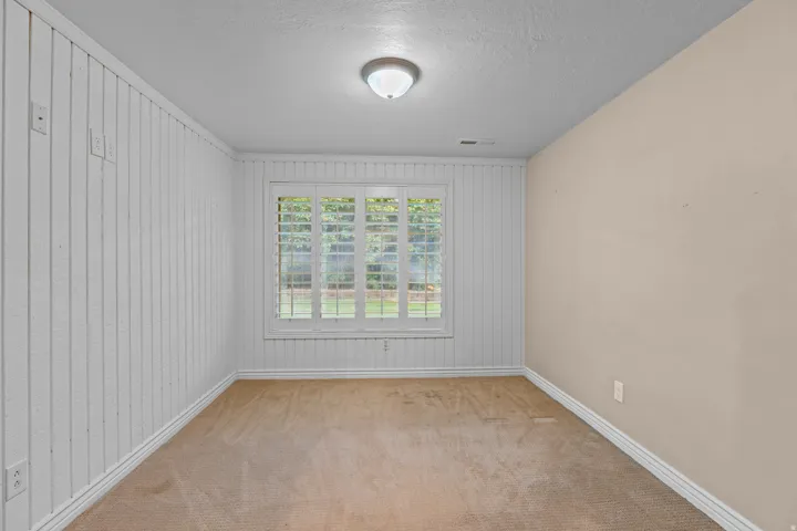 Window with plantation shutters, overhead lighting, textured ceiling, two-tone walls, and carpet flooring