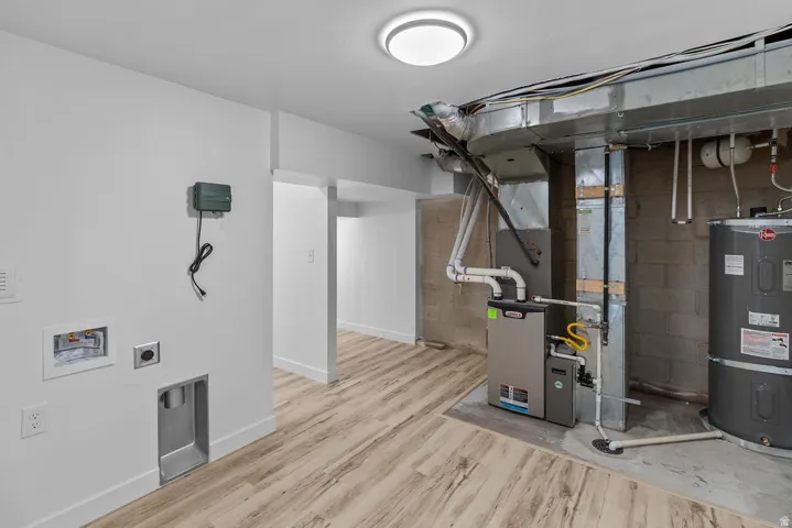 Utility area featuring wood-finish flooring, a contemporary flush mount light fixture, and accessible mechanical systems