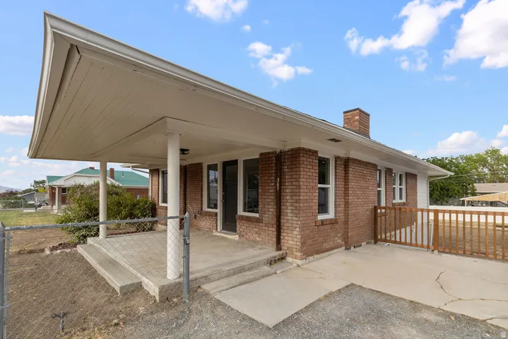 Brick exterior with an extended covered entry, concrete patio, and a chimney feature