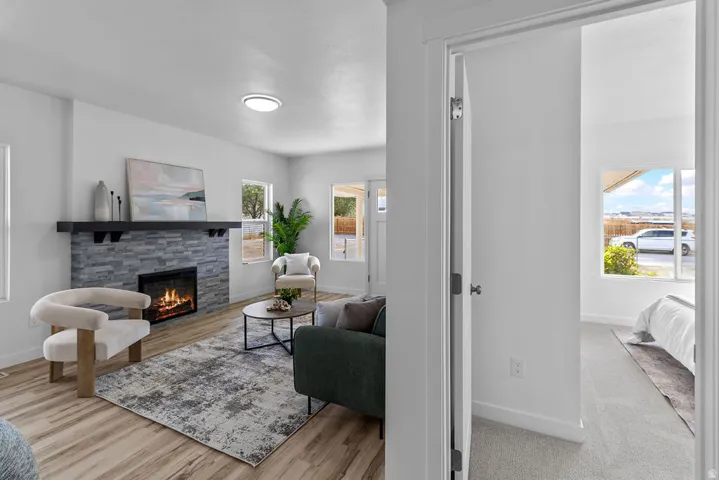 Living area with wood-finish flooring, a contemporary fireplace featuring a stacked stone surround, and a dark wood mantel