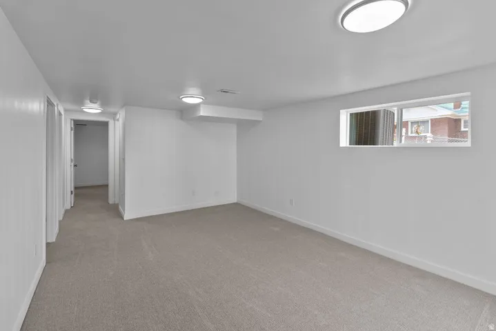 Recessed window, neutral-toned carpeting, white walls, and flush-mount ceiling lighting