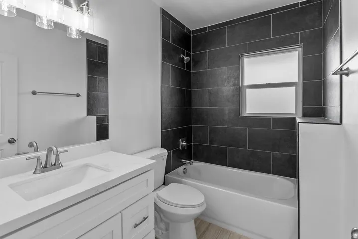 White vanity with an integrated sink, brushed nickel faucet, large mirror, and overhead lighting
