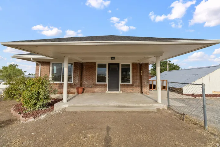 Brick exterior with a covered concrete porch and three support columns