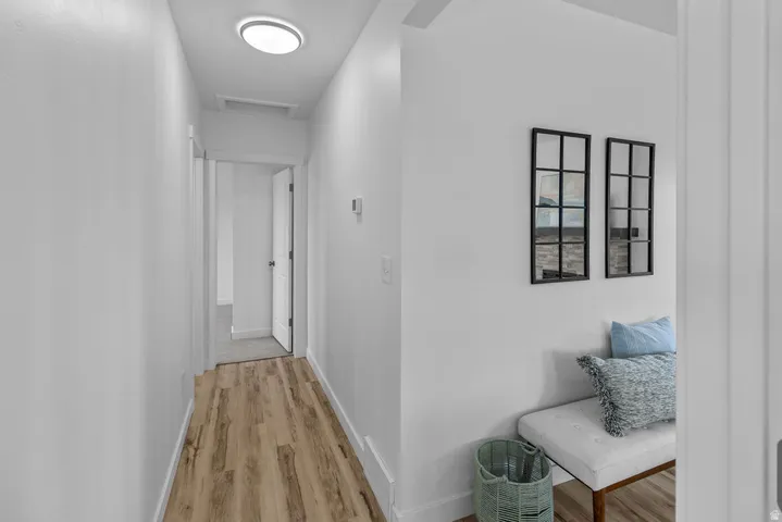 Hallway featuring wood-finish flooring, white walls, and a flush-mount ceiling light