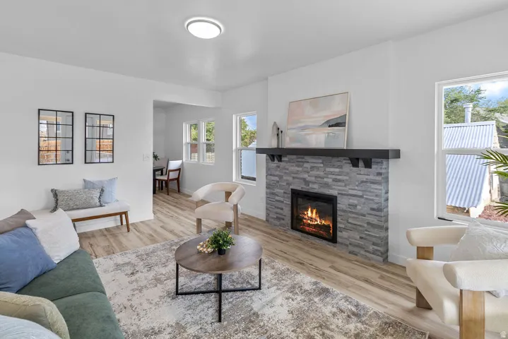 Warm living space featuring a stacked stone fireplace with a dark wood mantel, wood-finish flooring, and recessed lighting