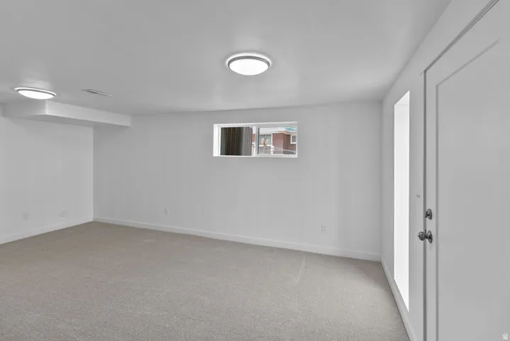 Recessed ceiling lights, neutral carpeting, white interior paint, and a window providing natural light