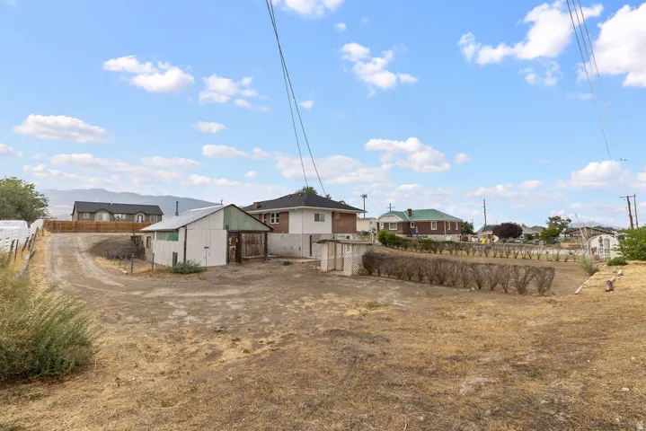 Expansive lot with a detached shed, mature hedging, and a white fence