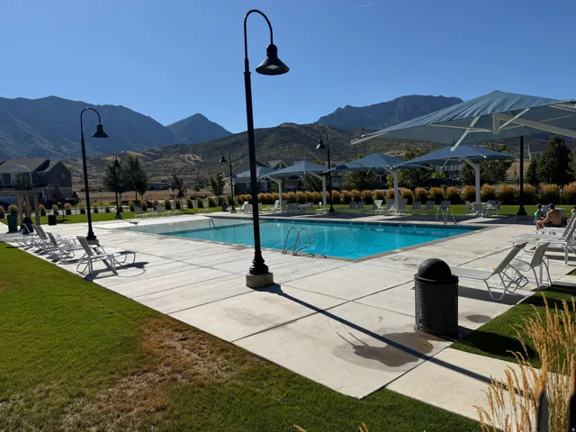 Outdoor swimming pool with integrated steps, surrounded by a concrete patio and green lawn