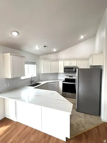 Kitchen featuring white cabinetry, stainless steel appliances, a white subway tile backsplash, white countertops, and wood-finish flooring