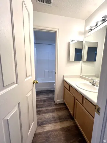 Wood-finish flooring, single vanity with a laminate countertop, and a built-in medicine cabinet