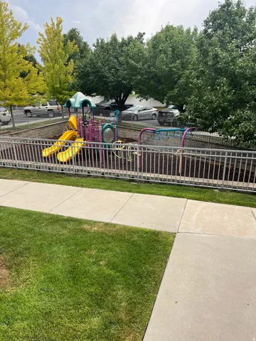 Recreational playground structure with two slides, a climbing feature, and a protective fence