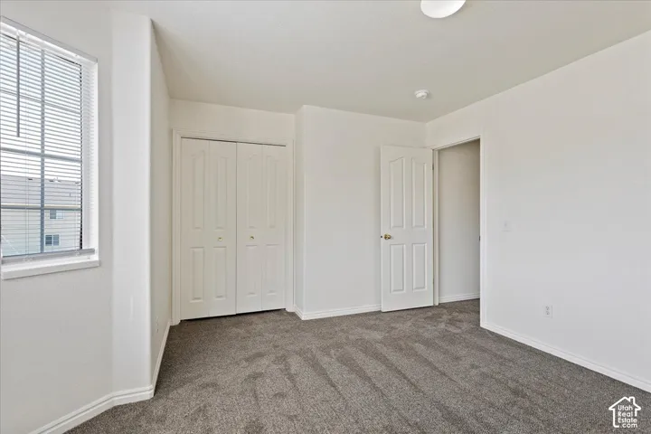 Neutral tone wall paint, textured carpeting, white trim, recessed lighting, and a white paneled door