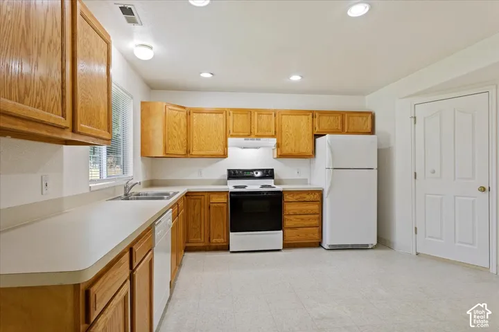 Kitchen featuring wood-finish cabinetry, solid surface countertops, a double basin sink, and recessed lighting