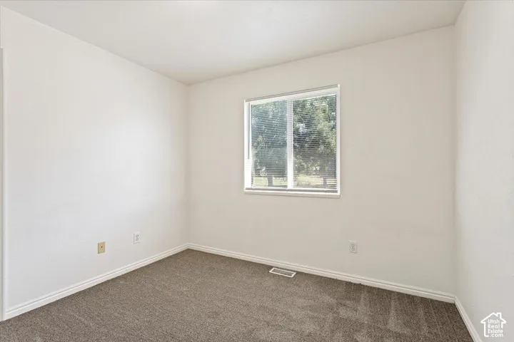 Neutral wall color, carpeted flooring, and a single window with blinds