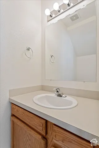 Vanity with wood-finish cabinetry, integrated oval sink, and a chrome faucet