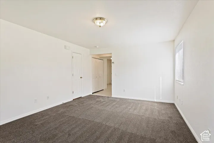 Neutral wall paint, plush carpeting, ceiling-mounted light fixture, white interior doors, and a window with blinds