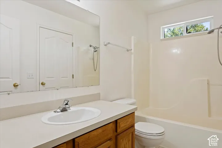 Vanity with an integrated sink, polished chrome faucet, wood-finish cabinetry, and an elongated mirror