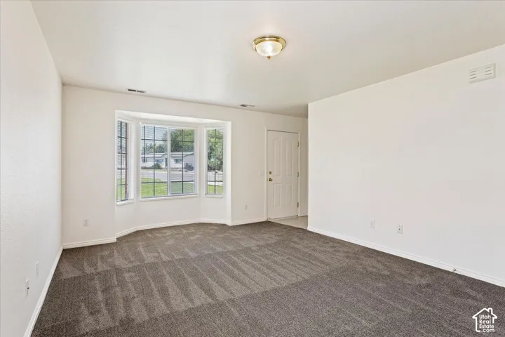 Expansive room featuring a bay window, neutral carpet flooring, white walls, and a recessed ceiling light fixture