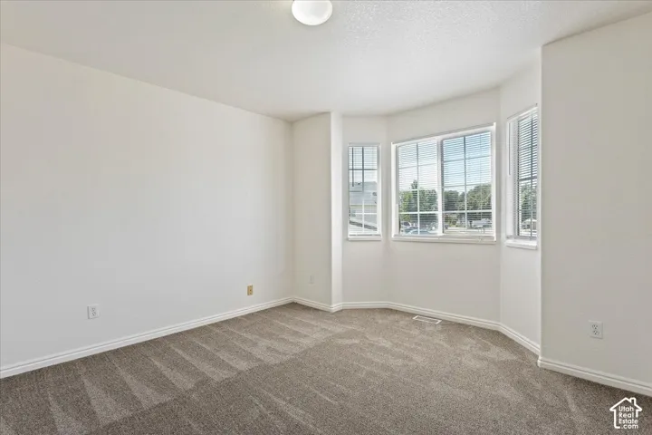 Bay window with multiple panes, neutral wall color, overhead lighting fixture, and patterned carpeting