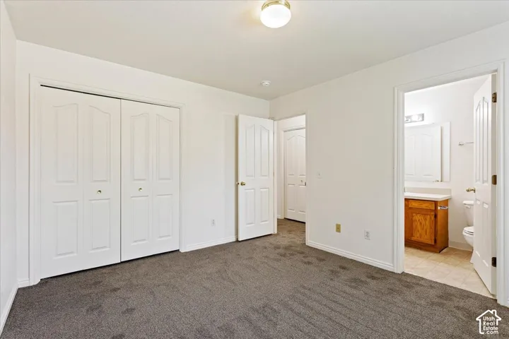 White interior walls, neutral carpeting, flush mount ceiling light fixture, white bi-fold closet doors, and white interior doors