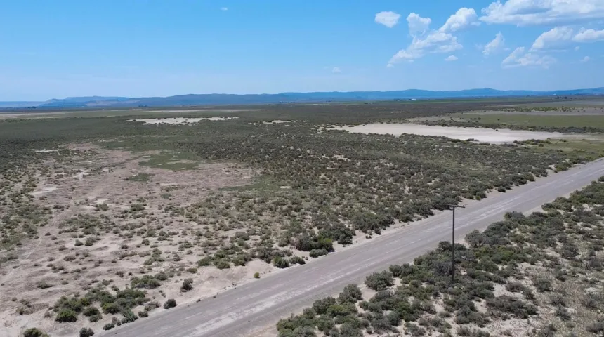 Expansive undeveloped land featuring a clear sky overhead and a distant mountain range