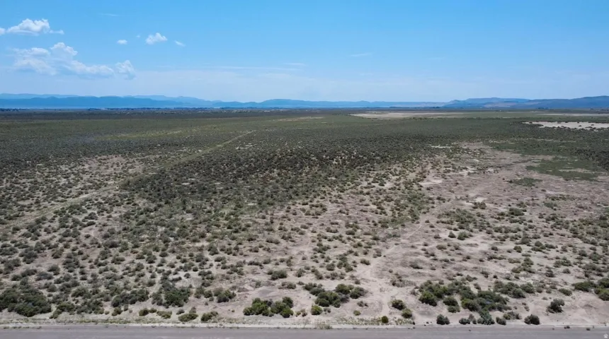 Expansive undeveloped land with natural vegetation and distant mountain ranges under a clear sky