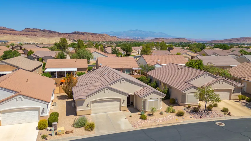 Tile roof property with an attached two-car garage, mature landscaping, and mountain backdrop