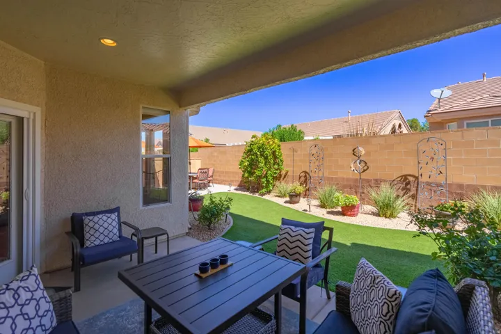 Covered patio with recessed lighting, stucco exterior, sliding glass door, and a private backyard featuring a brick privacy wall and artificial turf