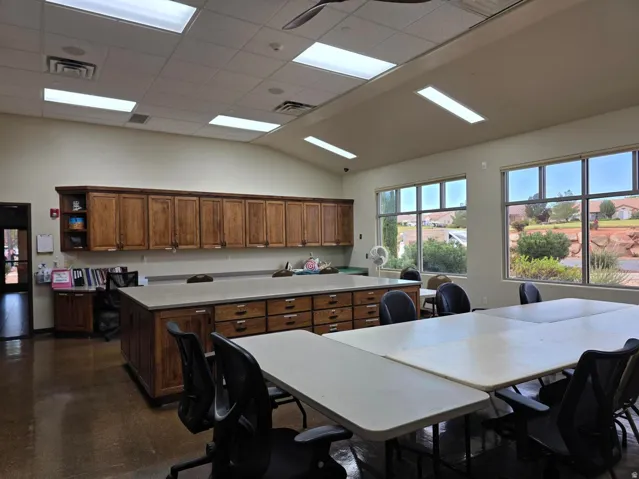 Spacious craft room featuring extensive wood cabinetry, large windows, recessed and fluorescent lighting, and a vaulted ceiling