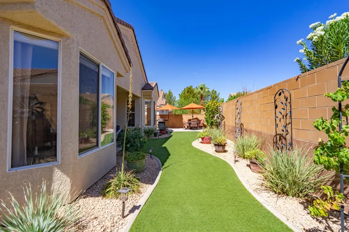 Expansive backyard featuring a manicured artificial turf lawn, decorative gravel landscaping, and a block wall perimeter