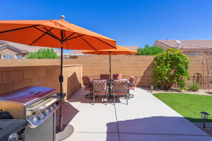 Paved patio area, artificial turf, perimeter block wall, and mature landscaping