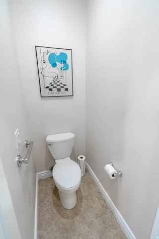Recessed toilet room with tile flooring and white walls
