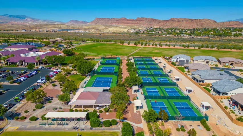 Multiple hard surface courts, extensive manicured grounds, adjacent golf course, and a distant mountain range