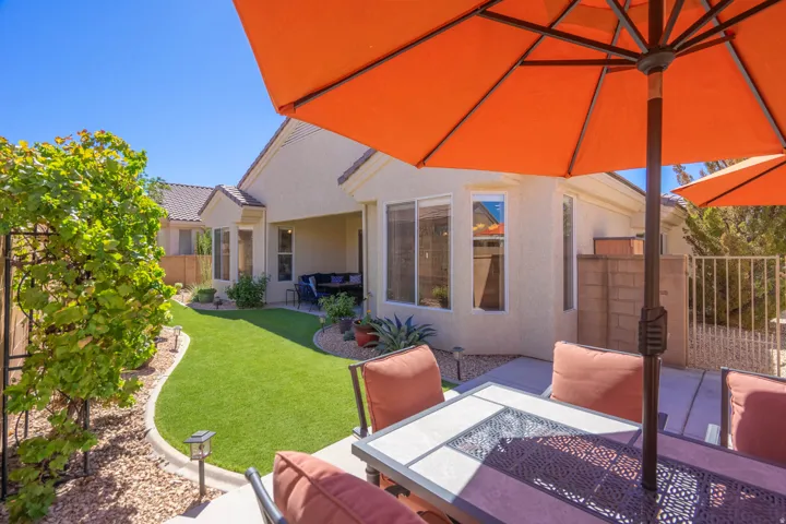 Expansive backyard featuring a manicured lawn, concrete patio, and gravel landscaping