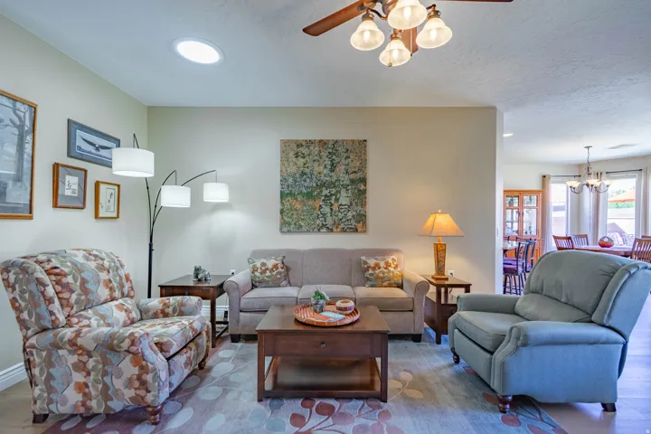 Solar tube ceiling light, ceiling fan with integrated lighting, wood-finish LVP flooring, and opening to dining room