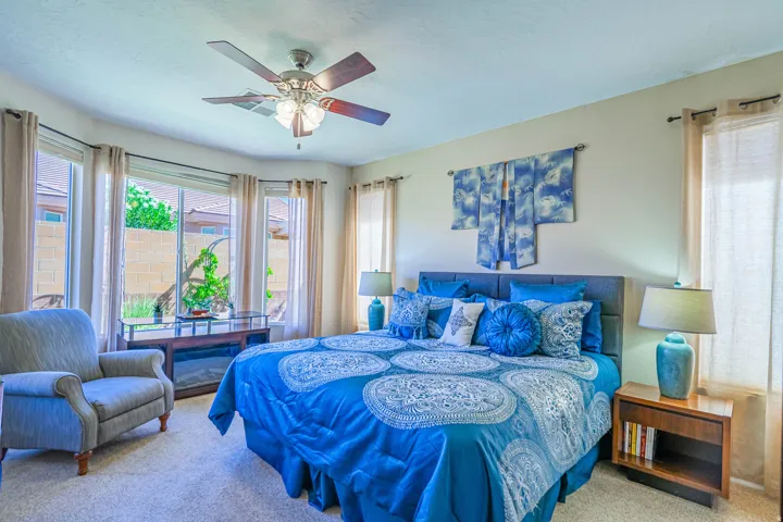 Primary Bedroom with bay window with multiple large panes, ceiling fan with integrated lighting, built-in electric fireplace, carpeted flooring, and neutral wall paint