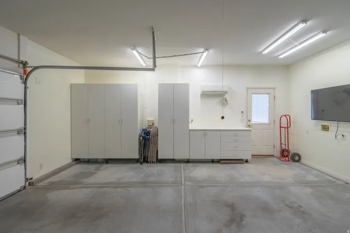 Concrete flooring, built-in cabinetry, recessed lighting, white entry door, and a wall-mounted flat-screen television