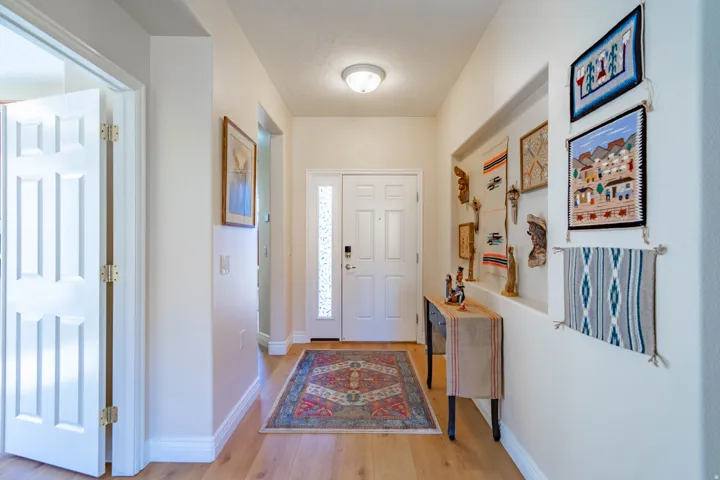 Wood-finish LVP flooring throughout, white interior doors, and a front entry door with a decorative glass insert