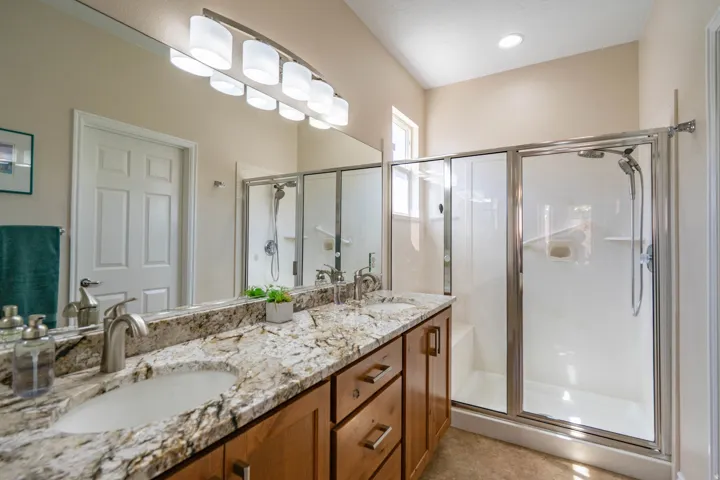 Primary bathroom with dual vanity with a granite countertop and undermount sinks