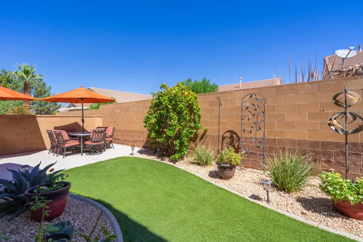 Private backyard with a concrete patio, artificial turf, and a gravel border