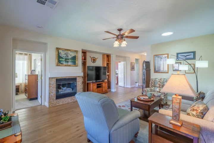 Wood-finish LVP flooring throughout, complemented by a fireplace with a stone-tile surround and mantel