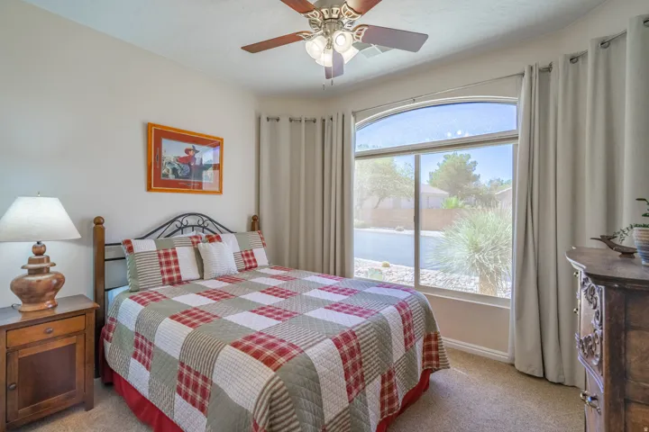 2nd bedroom with Arched transom over main bay window with exterior streetscape, ceiling fan, and neutral wall color