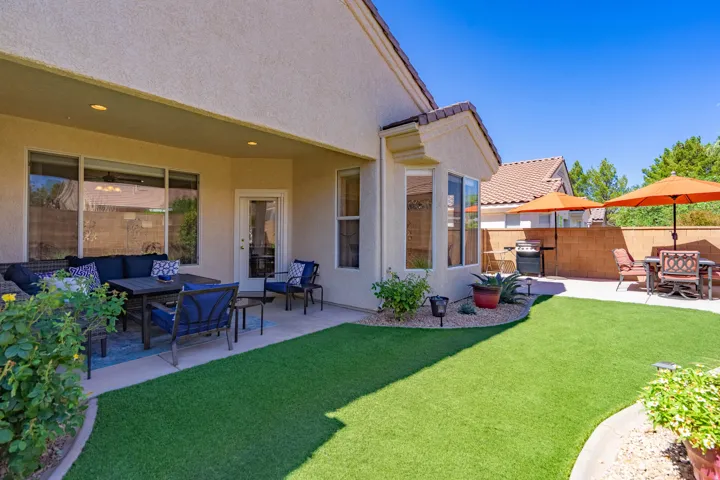 Expansive backyard featuring a covered patio, artificial turf, and a concrete paver patio