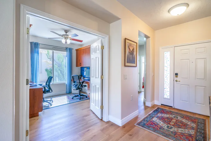 LVP flooring extending from the entryway into the interior, with double panel door with frosted glass sidelight, flush-mount ceiling light fixture, and an office space with built-in cabinetr