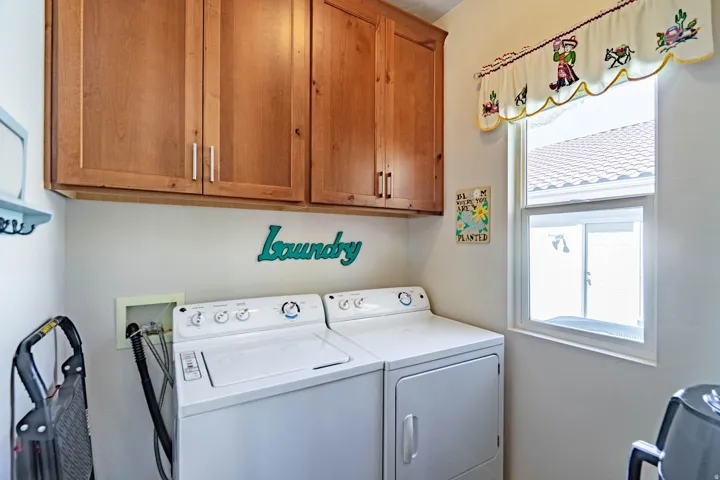 Upper wood-finish cabinetry, white framed window, and white walls
