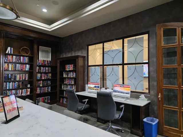 Library with Built-in bookcases, free computer station, coffered ceiling with recessed lighting, wood-finish paneling, and a large multi-pane window with frosted glass designs